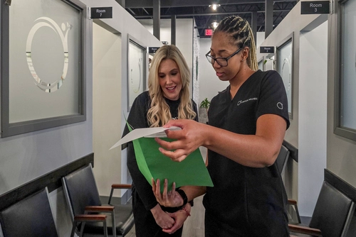 Home 47 Chiropractic staff member reviewing paperwork with a patient in hallway at Chiro Life Wellness.