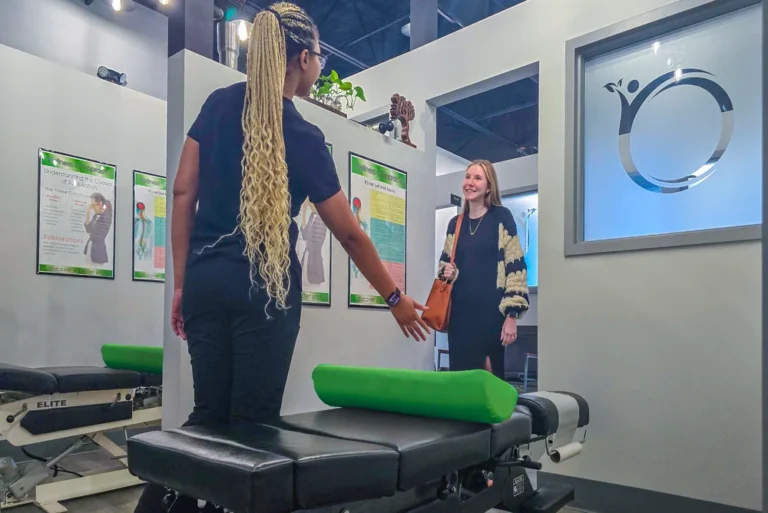 Home 43 Staff member welcoming a patient at a chiropractic treatment table.